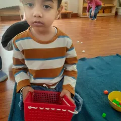 This child chose to explore a lacing activity by weaving the lace directly into the basket, not through the beads. We honor this creative deviation as a sign of purposeful work. It shows how children reveal their capabilities when given freedom within limits.