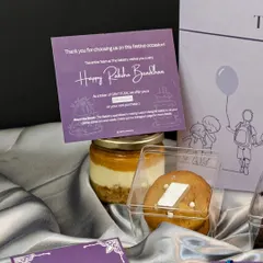 A close-up of the treats in our Rakhi hamper. You can see the layers of the Motichoor Cheesecake jar and the silver leaf on our special Kaju Katli cookie, all part of a box designed to bring back childhood memories.