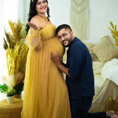 We love capturing the shared joy of expecting parents. This classic pose, with the partner listening to the baby bump, is a heartwarming way to document your connection and excitement. This shot was taken in our boho-chic studio setup.