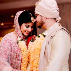 A beautiful, warm portrait of the couple after their wedding ceremony. Their shy smiles and the garland exchange show the quiet joy of being newly married.