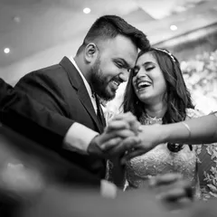 Surrounded by the hands of their loved ones, the couple shares a private laugh. This creatively framed shot captures a moment of joy and connection amidst the celebration.