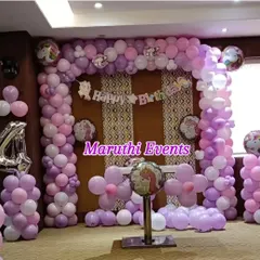 A beautiful unicorn-themed birthday party with a full balloon arch in shades of purple and pink. Unicorn foil balloons and a 'Happy Birthday' banner complete this whimsical setup.