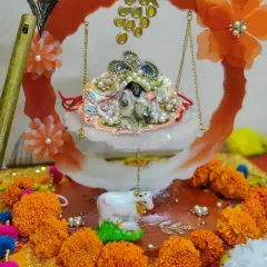 A complete festive setup for Janmashtami featuring my handmade resin jhulla. The orange and white swing is the centerpiece for Laddu Gopal, surrounded by flowers and his flute.