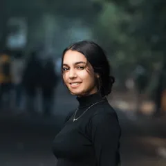 We captured this friendly and engaging portrait during an outdoor lifestyle session. The blurred background suggests a bustling environment, while the focus remains on her warm smile, making it ideal for a professional profile.