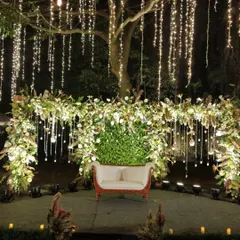 We transform outdoor spaces into enchanted wonderlands for evening receptions. Here, we used cascading fairy lights and a lush floral arch to create a magical photo backdrop, perfect for capturing memories under the stars.