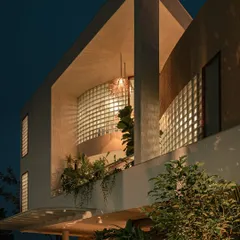 This night view shows how the integrated lighting and plants turn the home's facade into a beacon. The greenery on the balcony is highlighted, adding depth and life to the architecture.