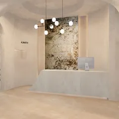 The reception desk at the studio is a monolithic piece that appears to be carved from a single stone, reflecting the Wabi-Sabi aesthetic. Behind it, a striking textured mirror from SICIS Italy serves as a piece of art, adding depth and a touch of luxury.