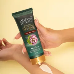 A texture and application shot for Biofresh Botanicals' face wash. This image demonstrates the product's creamy consistency and is styled to convey a sense of clean, gentle skincare, perfect for beauty brand websites and social content.