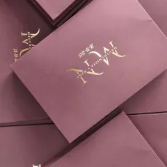 An angled view of the portwine envelope, highlighting the clean lines and the shimmer of the gold foil monogram.