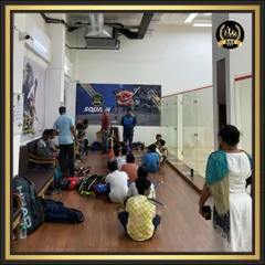 A group of young players listening intently to their coach before a squash session. We focus on providing quality coaching for all age groups in a supportive environment.