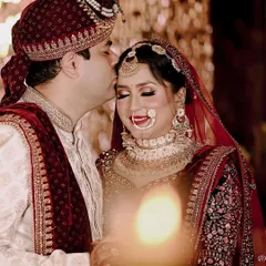 A tender moment between the bride and groom on their wedding day. The groom's gentle kiss on her forehead is a timeless expression of love and care.