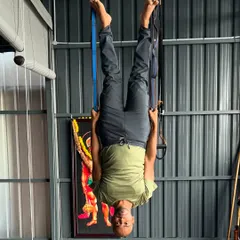 Demonstrating an inverted aerial yoga pose. This type of inversion uses the hammock to support the body, allowing for spinal decompression and improved blood flow without any pressure on the neck or shoulders.