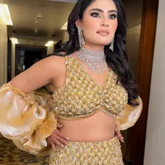 A full-length shot showcasing the complete reception look. The gold lehenga is perfectly complemented by the warm, shimmery makeup and voluminous hair, creating a cohesive and glamorous statement.