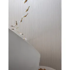 A detail of the custom light fixture, with bird-like forms appearing to fly up the stairwell, adding a whimsical touch to the minimalist space.