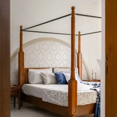 A view into the bedroom, where a classic four-poster bed with an arched, patterned headboard creates an elegant and serene focal point.