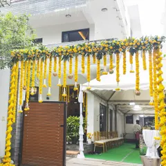 A grand entrance arch lavishly decorated with yellow marigold garlands sets a festive and traditional tone for a Myra ceremony, welcoming guests with warmth and color.