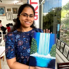 A smiling participant shows off the beautiful waterfall scene she painted on canvas. My guided painting sessions make it easy for anyone to create a masterpiece.