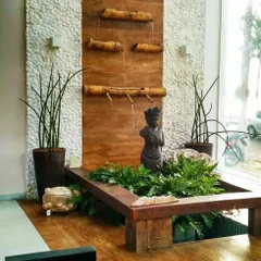 This indoor water feature combines natural elements like a stone wall, a wooden panel, and bamboo-style spouts. It's a beautiful way to bring the soothing sounds and sights of water into your home.