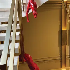 A detailed shot of the magnificent red panther sculptures. Their high-gloss finish provides a bold pop of color against the neutral tones of the staircase and walls.