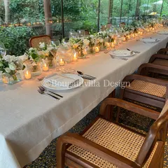 A beautifully set long table for an intimate gathering in our Central Pavilion. The clean white linens, simple glassware, and rows of candles and white flowers create a sophisticated and welcoming atmosphere.