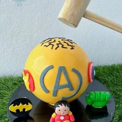 Get ready to smash! This is our super popular superhero pinata cake. The yellow chocolate sphere is decorated with Avengers and Batman logos and comes with a hammer to crack it open, revealing a fun surprise of candies inside.