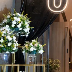 Step into the grandeur of a 50th birthday extravaganza. The entrance was designed to be dramatic and elegant, with beautiful white floral arrangements set against a sparkling black backdrop to welcome guests to the surprise party.