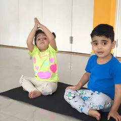 Two children practice a seated yoga pose, showing great focus. Our indoor classes incorporate elements of yoga and stretching to improve flexibility and concentration.