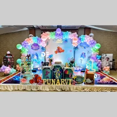 An enchanting underwater mermaid theme for Punarvi's first birthday. This grand setup includes characters from 'Finding Nemo', mermaid cutouts, and a stunning balloon arch that mimics ocean waves.