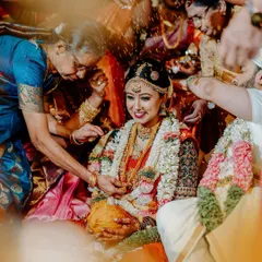 Surrounded by the blessings of family, the bride smiles radiantly during the Akshate ritual. This candid shot captures the overwhelming love and joy of a traditional South Indian wedding ceremony.