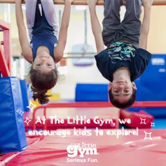 Two children hang upside down from the bars, smiling for the camera. This playful exploration builds significant upper body and grip strength, while also improving spatial awareness and confidence.