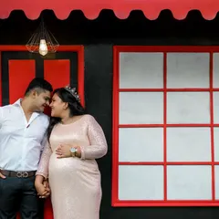 Your love story is at the heart of it all. This shot shows a quiet, intimate moment between an expecting couple, captured against one of the modern, vibrant backdrops at our Bangalore studio.
