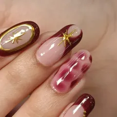 A close-up of the details on this beautiful manicure. You can see the crisp gold border around the oval nail and the subtle shimmer in the blooming gel art.