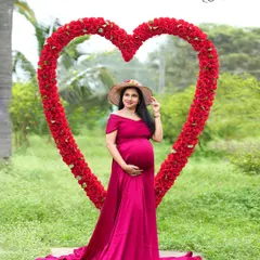 Framed by love. This striking portrait features our large, red floral heart prop, perfectly framing the mother-to-be in her beautiful magenta off-shoulder gown.