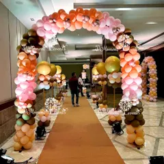 A beautiful balloon archway in earthy and pastel tones lines the entrance path, creating a warm and inviting welcome for guests.