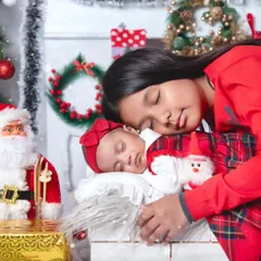There's nothing more special than the bond between siblings. Here, an older sister gently cuddles her sleeping newborn sister in a festive Christmas-themed setup, creating a memory the family will cherish forever.