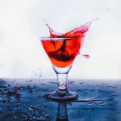 A dynamic splash shot of a red beverage in a cocktail glass. Freezing the motion of the liquid creates an energetic and exciting image, perfect for a drink menu or promotional ad.