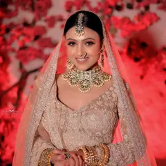 We love capturing the genuine smiles and happy moments. This portrait of a bride in a beautiful pastel lehenga against a vibrant red floral background shows how we blend candid emotion with a perfectly styled shot.