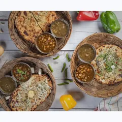 A top-down view of our hearty Amritsari Chole Kulche, served in traditional wicker baskets with all the classic accompaniments. It's a taste of Punjab on a plate.