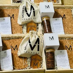 Preparing a bulk order of employee welcome kits. Each hamper for 'Modern Spaaces' is consistently arranged with branded items to ensure every new joiner receives the same warm welcome.