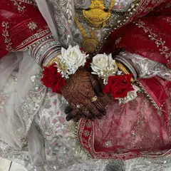 The bride's hands, adorned with her engagement rings and floral bracelets, showcasing the beautiful, dark henna stain.