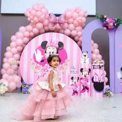 A dreamy Minnie Mouse theme for a little girl's birthday. This setup includes custom-arched backdrops, a large balloon bow, and character prints, all in a lovely pink and purple color scheme.