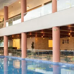 The poolside at the Sona Vistaas Clubhouse, framed by terracotta-colored columns. The design connects indoor and outdoor leisure areas, with the upper-level balcony overlooking the pool to foster a sense of community and shared experience.