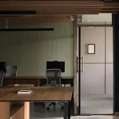 We used a combination of materials to define the main workspace. Sound-absorbing fabric panels on the wall in a muted green hue contrast with the warmth of the wooden desks and ceiling baffles, creating a productive yet comfortable environment.
