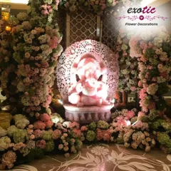 This breathtaking Ganpati decoration features an intricately carved idol illuminated in pink, nestled within a grotto of pastel-colored roses and hydrangeas. The design creates a magical and divine aura, making the idol the absolute center of attention.