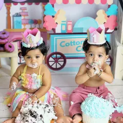 A twin cake smash is double the fun and double the mess. These two one-year-olds are enjoying their individual cakes in a colorful candyland-themed studio setup.