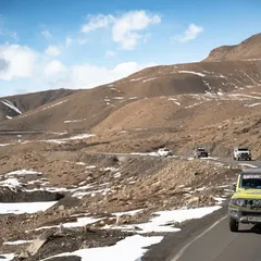A series of images showing a convoy of 4x4 SUVs navigating the winding, mountainous roads of Spiti. These shots highlight the challenging yet rewarding nature of the expedition.