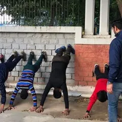 Physical conditioning is non-negotiable. Here, I am supervising students as they build core and shoulder strength with wall handstands.