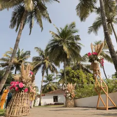 We created a "nature's aisle" for this tropical-themed event, lining the pathway with large rustic baskets filled with pampas grass and pink roses. This design beautifully blends with the outdoor venue and its towering palm trees.