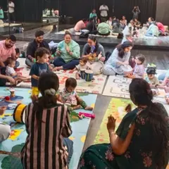 Our classes are a community circle where every family participates. You can see parents and children all engaged in a group music-making activity, which is the foundation of our sessions.
