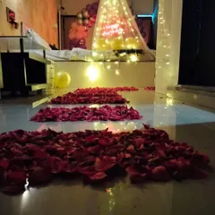 A romantic pathway of red rose petals leading to a bed decorated with a light-up canopy for a special surprise.